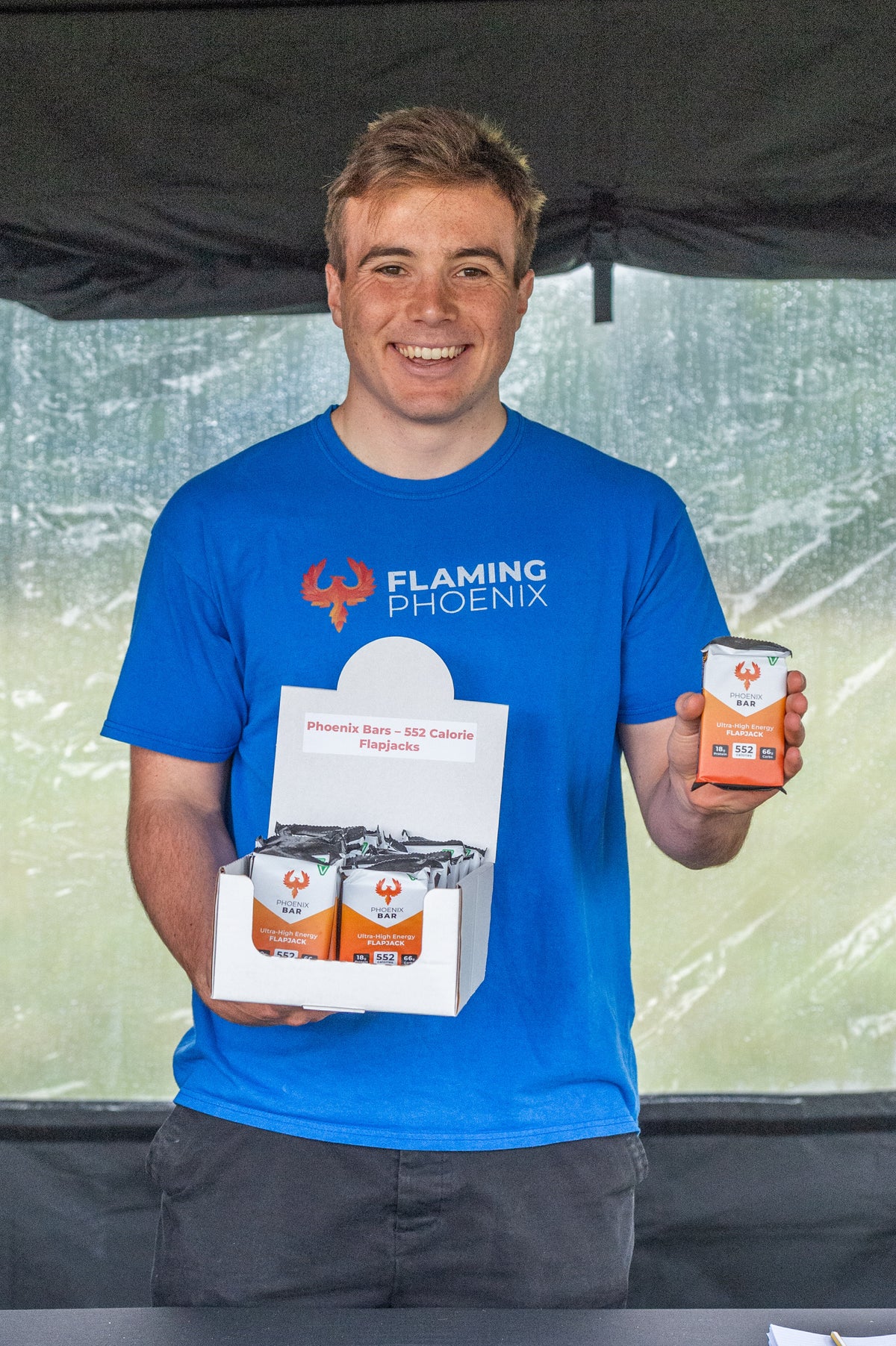 James Frost, founder of Flaming Phoenix, smiling and holding a box of Phoenix Bars